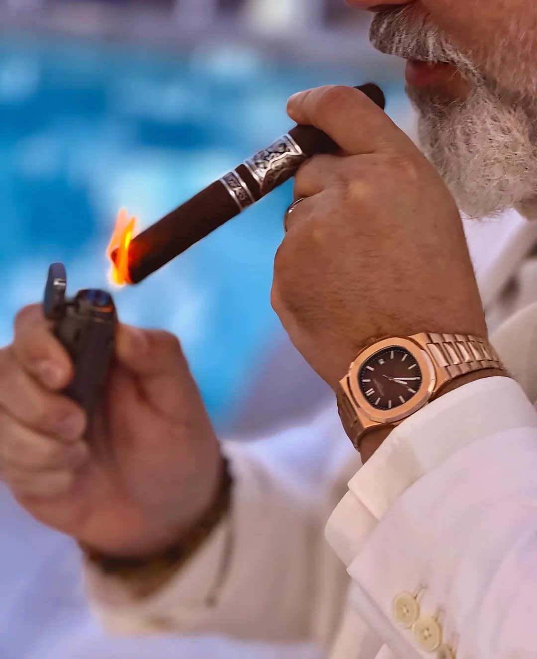 A Rose Gold Reserve cigar being lit, a rose gold watch on the wrist